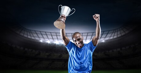 Composition of sportsman celebrating victory, holding trophy at stadium