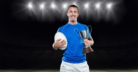 Composition of male rugby player celebrating victory, holding trophy at stadium