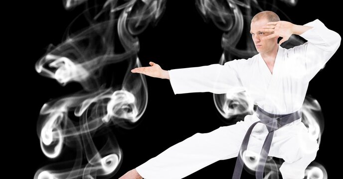Composition of male martial artist over trails of smoke on black background