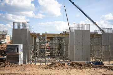 Modern building under construction. Workers set up scaffolding and formwork for pouring concrete.