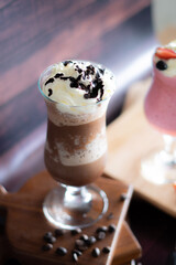 Chocolate frappe in a tall glass with syrup and whipped cream.