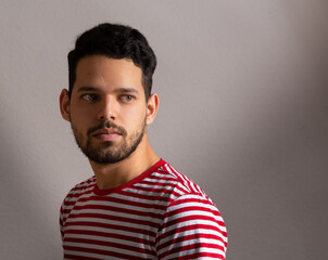 Obraz premium Young latino man turn his head and look back in a studio shot. He is in his 20s and looks serious