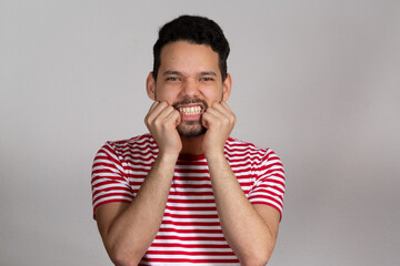 Young latino man with angry expression placing his fists in front of his face. He is in his 20s and poses for a studio shot.