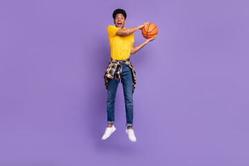 Fototapeta na wymiar Full length body size view of attractive cheerful guy jumping playing basketball having fun isolated over violet purple color background
