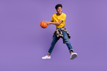 Fototapeta na wymiar Full length body size view of attractive cheerful guy jumping throwing ball isolated over violet purple color background