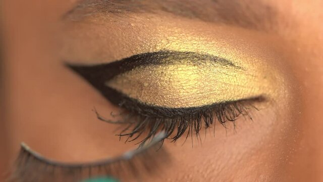 cropped view of african american woman with closed eye applying eye liner