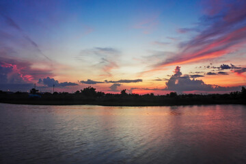 The rainy season sky, the evening sunset light, the sky and the clouds turn pink at the riverside beautifully.