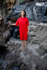 An elegant fashionable fresh beautiful woman in a red vintage dress with rocks background. 
