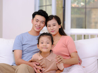 Obraz premium A happy family of three is sitting on the sofa in the living room