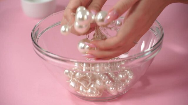 cropped view of woman taking hair pins with pearls on pink