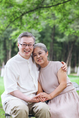 Happy old couple sitting on chairs in outdoor park