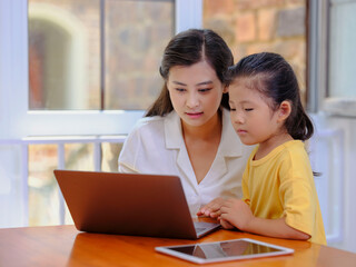 Young Happy mother and daughter use laptops