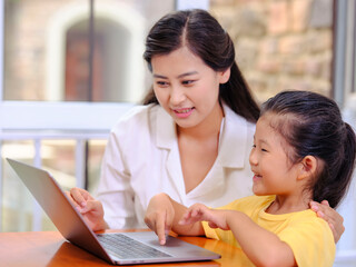 Young Happy mother and daughter use laptops
