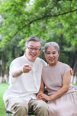 Happy old couple sitting on chairs in outdoor park