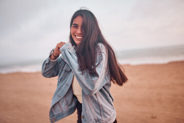Mujer Joven latina posa caminando en la arena durante un bello atardecer.. Joven feliz en la playa