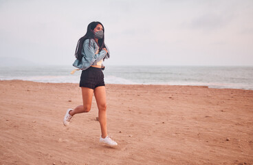 Mujer Joven latina saltando en la arena durante un bello atardecer.. Joven feliz en la playa