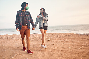 Pareja de jóvenes enamorados caminan por la playa durante un bello atardecer.. Jóvenes felices jugando en malecón de la playa. Amor de pareja