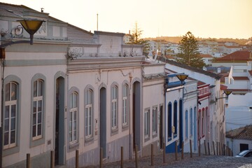 Old facades of houses on a descending street at sunset in the city of Lagos , Algarve, Portugal