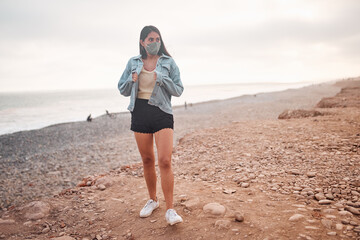 Mujer Joven latina se quita la ropa durante un bello atardecer.. Joven feliz  con mascarilla en la playa