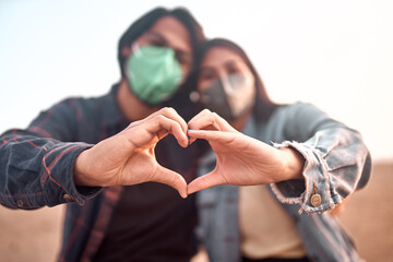 Pareja de jóvenes enamorados forman un corazón con sus manos durante un bello atardecer.....