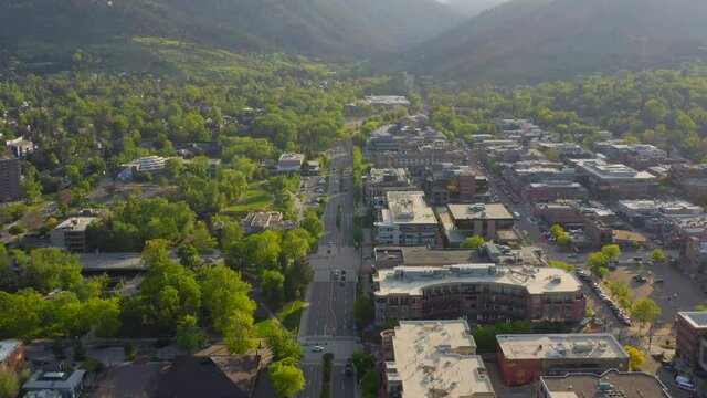 Aerial pan up reveal of beautiful mountain vista and bright green trees in downtown Boulder Colorado during an evening sunset with warm light on the rocky mountain town and summer landscape
