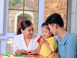 Obraz premium A happy family of three doing paper cutting in the living room