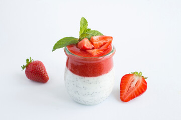Pudding with chia seed and strawberry in the glass jar on the white background. Copy space. Close-up.