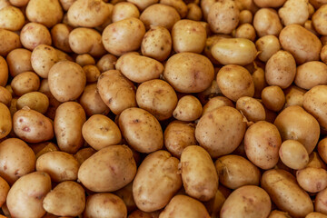 A lot of fresh young potatoes on the counter in the market. Healthy food, vitamins and veganism. Top view. Background.