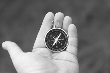Old classic navigation compass in hand on natural background as symbol of tourism with compass,...