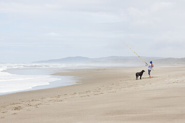 Child and dog Surf Perch fishing on the sandy beach of the Southern Oregon Coast