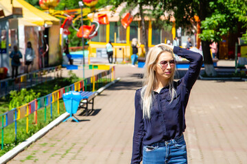 portrait of a blonde girl walking in a city park