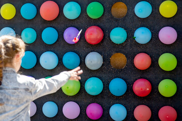 amusement park, a girl throws darts at balloons
