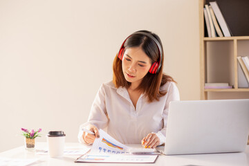 Asian Young business woman working at home with laptop and papers on desk.