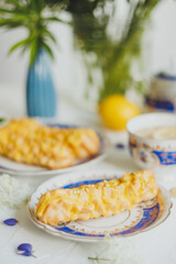 Lemon eclairs and lemon tea, in a vintage tea set, and flowers, over white background.