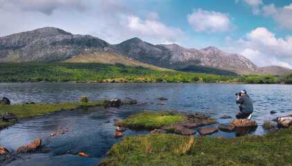 Beautiful landscape scenery with photographer by th Lough Inagh with mountains in the background at Connemara National park in county Galway, Ireland 