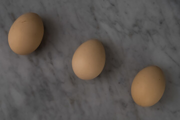 Three eggs arranged in a row on a marble table.