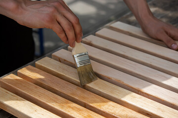 Painting wooden furniture with varnish. a man hides a tree with varnish.