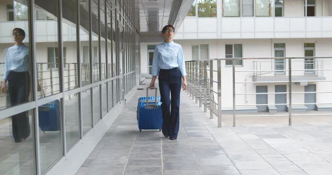 Businesswoman dragging suitcase luggage bag walking to passenger boarding in airport