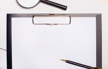 On a light background, a magnifying glass, a pen and paper with a place to insert text. Business...