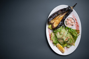 top view of baked eggplant with chinese cabbage and sauce on black background
