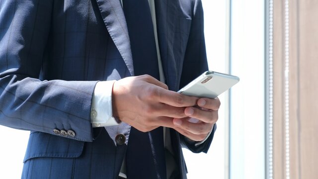 スマホを操作しているサラリーマン男性 - Powered by Adobe