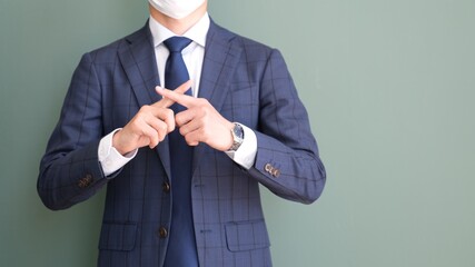 指で×を作るマスクをしたサラリーマン男性