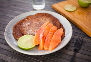 healthy breakfast of pieces of salted smoked salmon with buckwheat pancakes and lime