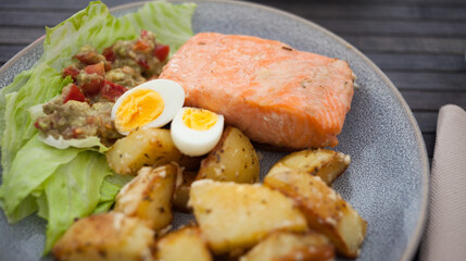 baked salmon fillet with fried potato wedges, homemade guacamole and quail eggs halves