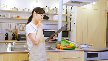 バインダーをもってご飯の献立に悩む家事代行の女性作業員