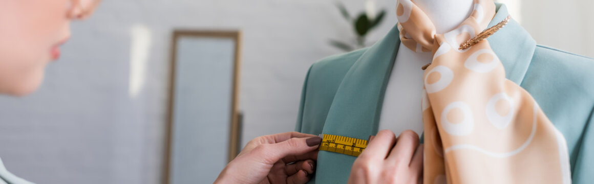 Cropped view of designer measuring jacket on mannequin in atelier, banner