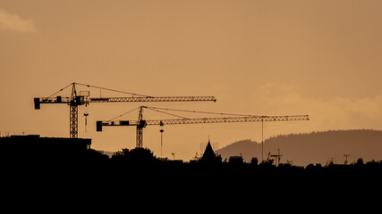 Two Construction Cranes Silhouette at Sunset on Dublin Sky