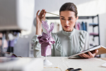 Mannequin with dress near blurred designer with notebook in studio