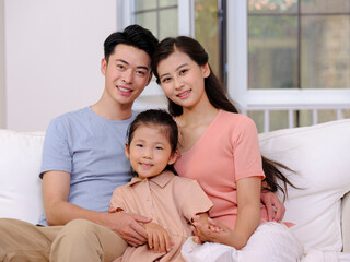 Fototapeta premium A happy family of three is sitting on the sofa in the living room