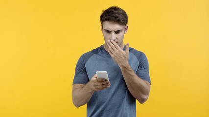 Offended man using mobile phone isolated on yellow